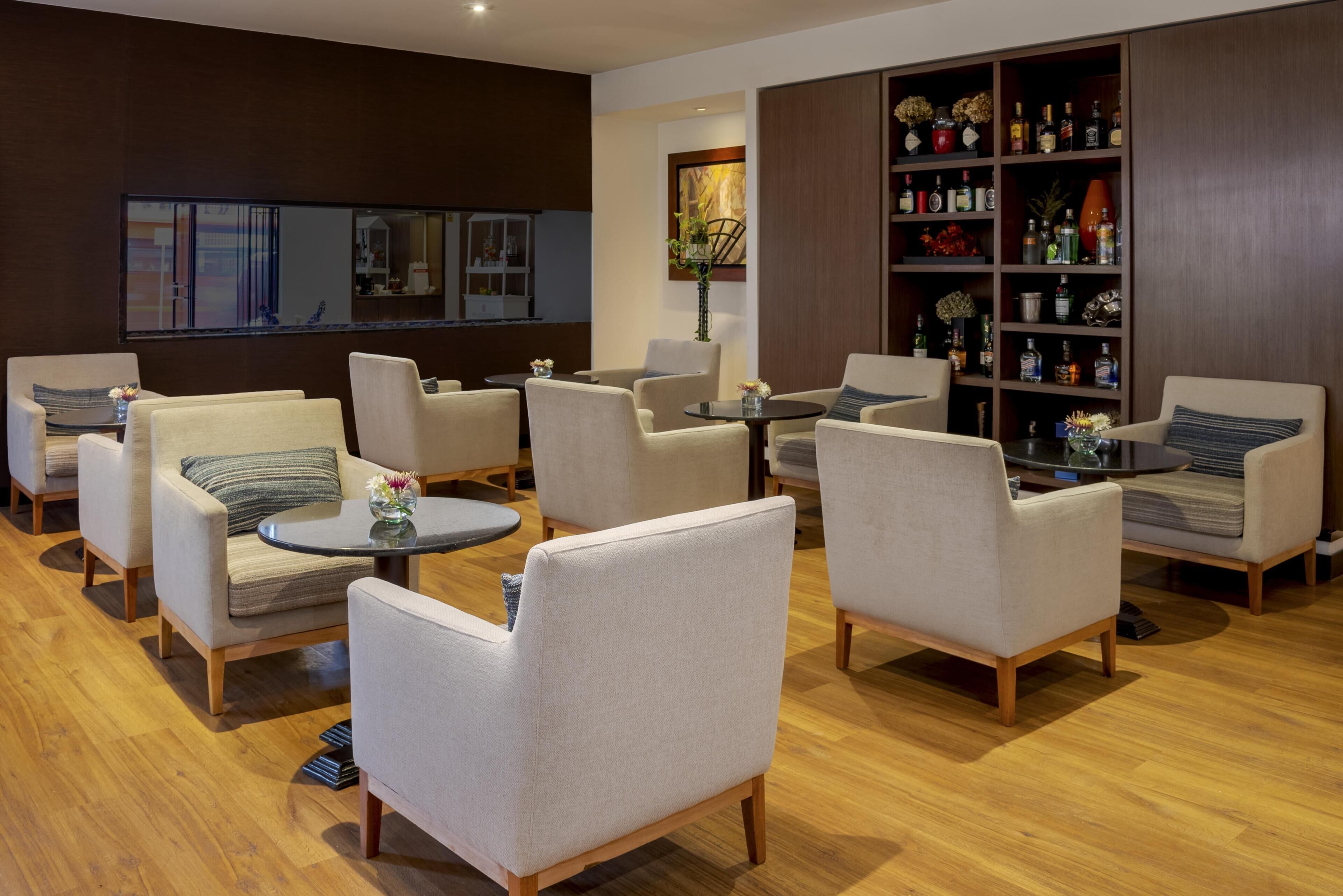 A modern living room with multiple sofas, a coffee table, and a bookshelf filled with books and decorative items.
