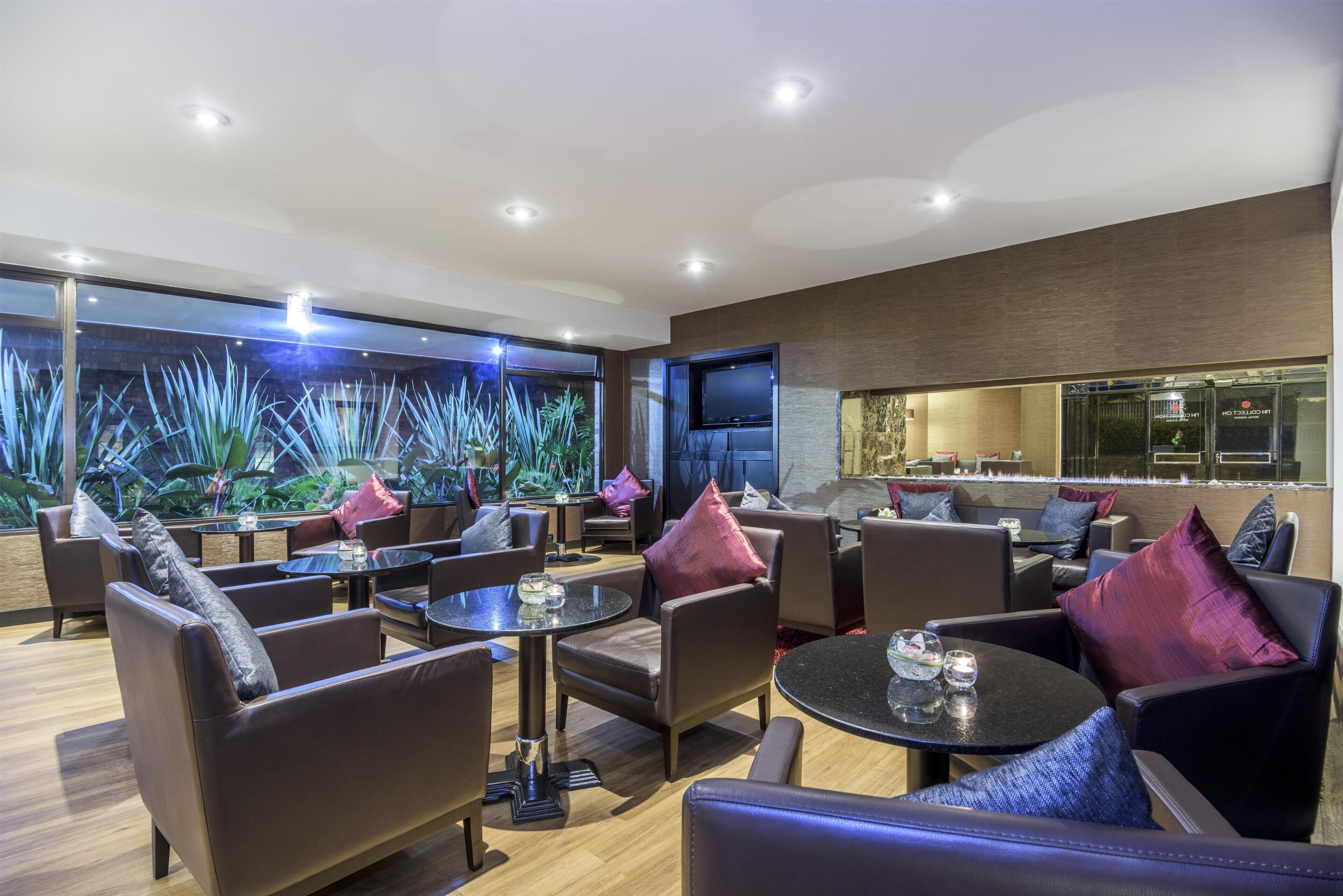 Una zona relax moderna con divani in pelle, tavolini rotondi e una parete interamente dedicata a un grande acquario.