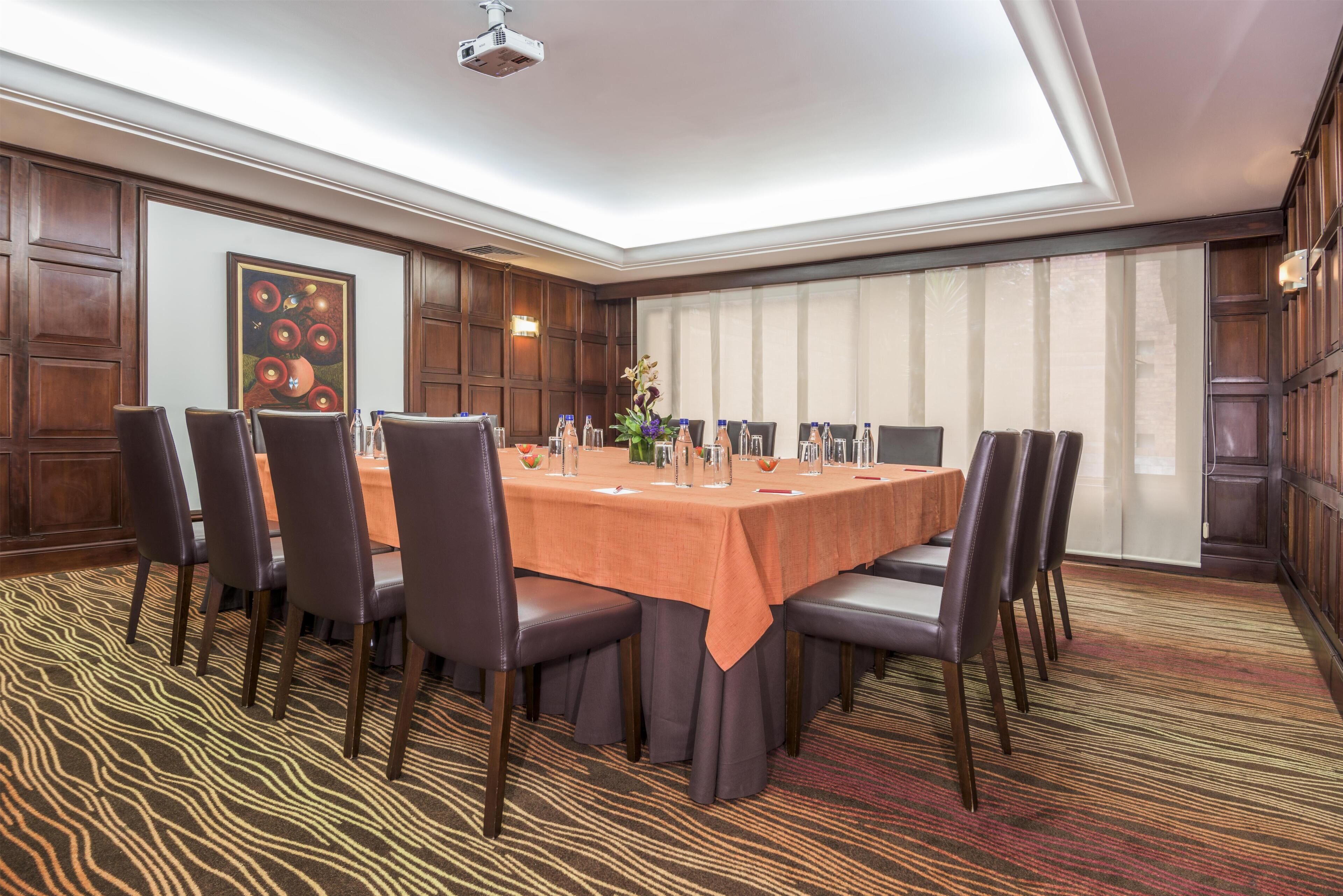 A conference room with a long table, chairs, a projector, and a large window.