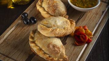 Una tabla de madera con tres pasteles, una botella de aceite y dos recipientes con salsas para mojar.