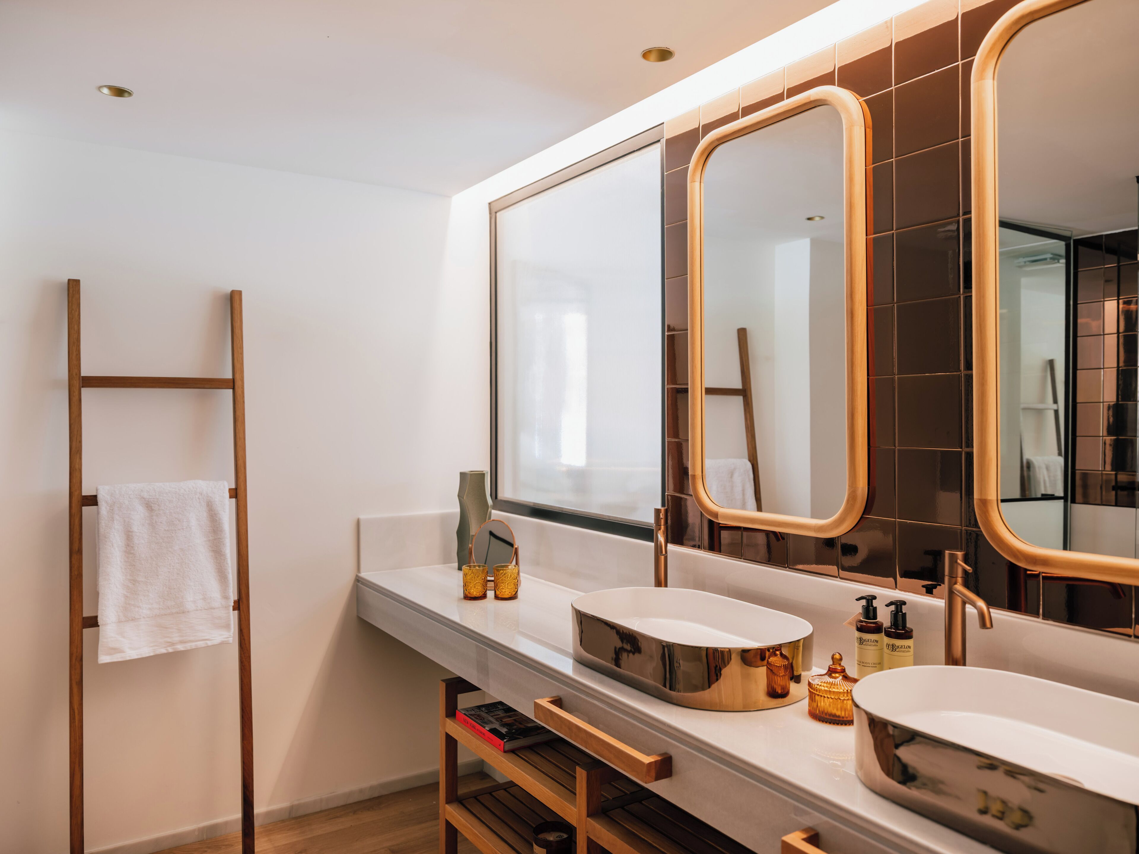 A modern bathroom with a wooden ladder, two sinks, and a large mirror.
