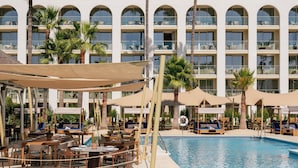 A hotel pool area with lounge chairs, umbrellas, and a clear blue pool.