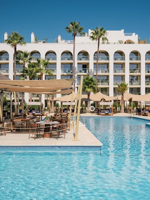 A hotel pool area with lounge chairs, umbrellas, and a clear blue pool.