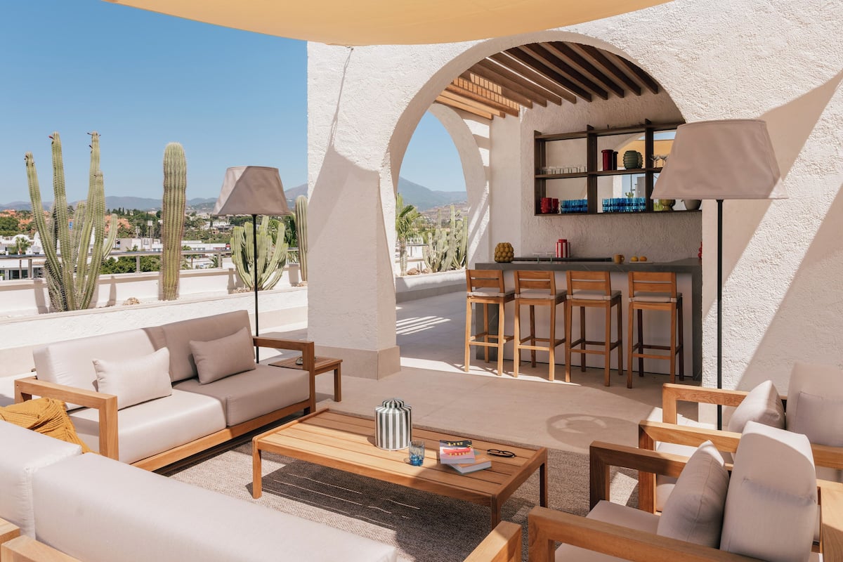 An outdoor seating area with a bar, white walls, and cacti.