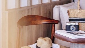 Une chaise en bois, un chapeau de paille, un appareil photo ancien et un sac tressé sont posés sur une table ronde.