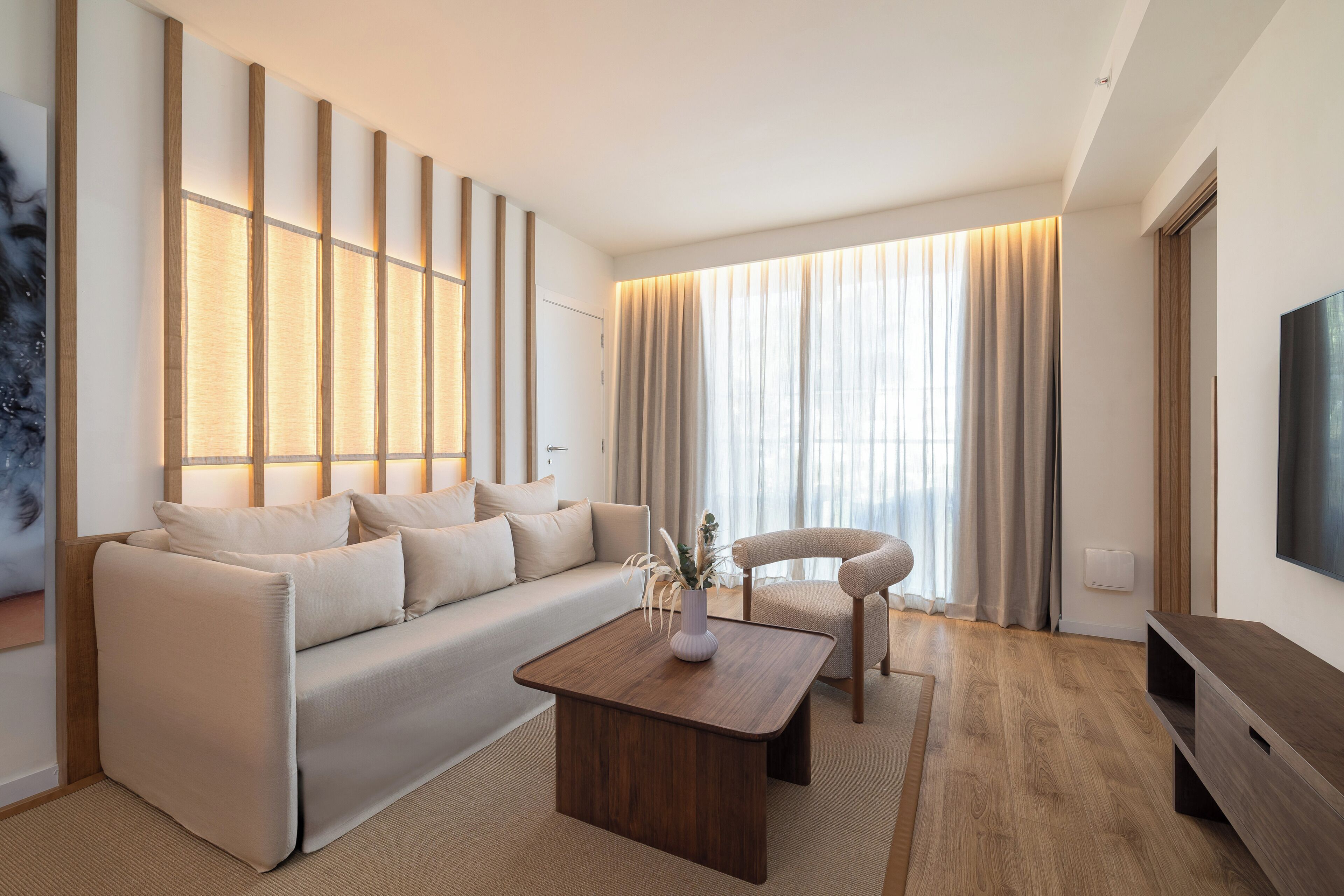 A modern living room with a sofa, a wooden coffee table, a chair, and a TV.