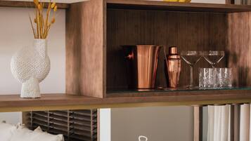 Una cocina moderna con un armario de madera, un florero con flores secas, una taza amarilla, un coctelero de cobre y una estación para café.