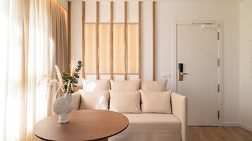 A modern living room with a beige sofa, a round wooden table, and a decorative vase.