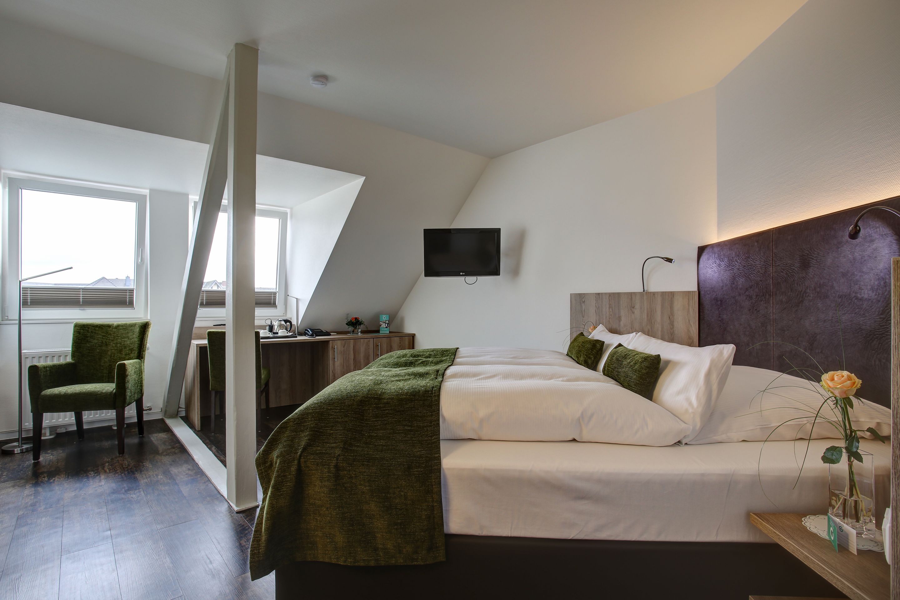 Un dormitorio moderno con una cama, un escritorio y un televisor.