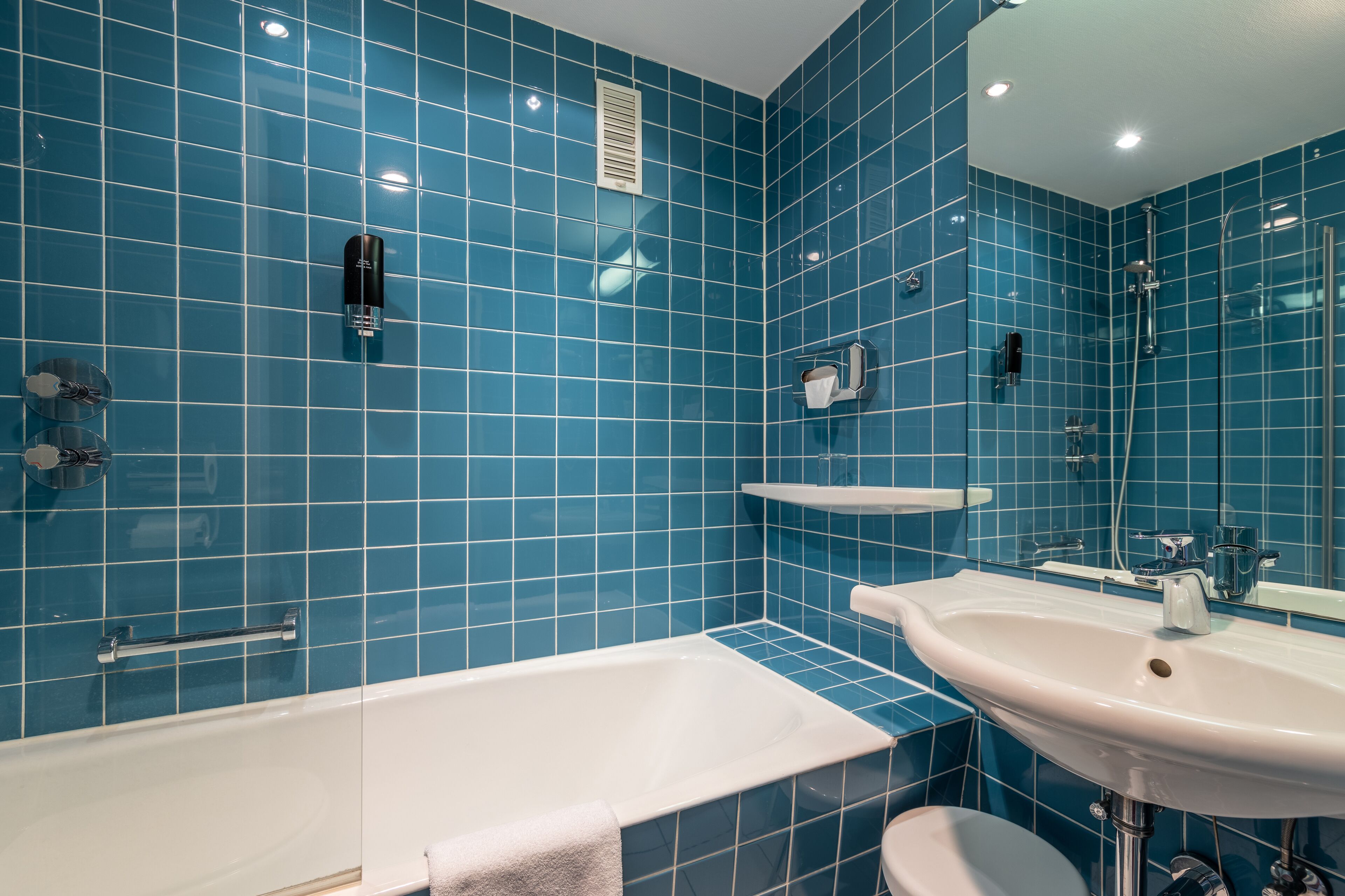 Ein Badezimmer mit blauen Fliesen, einer Badewanne, einem Waschbecken und einer Dusche.