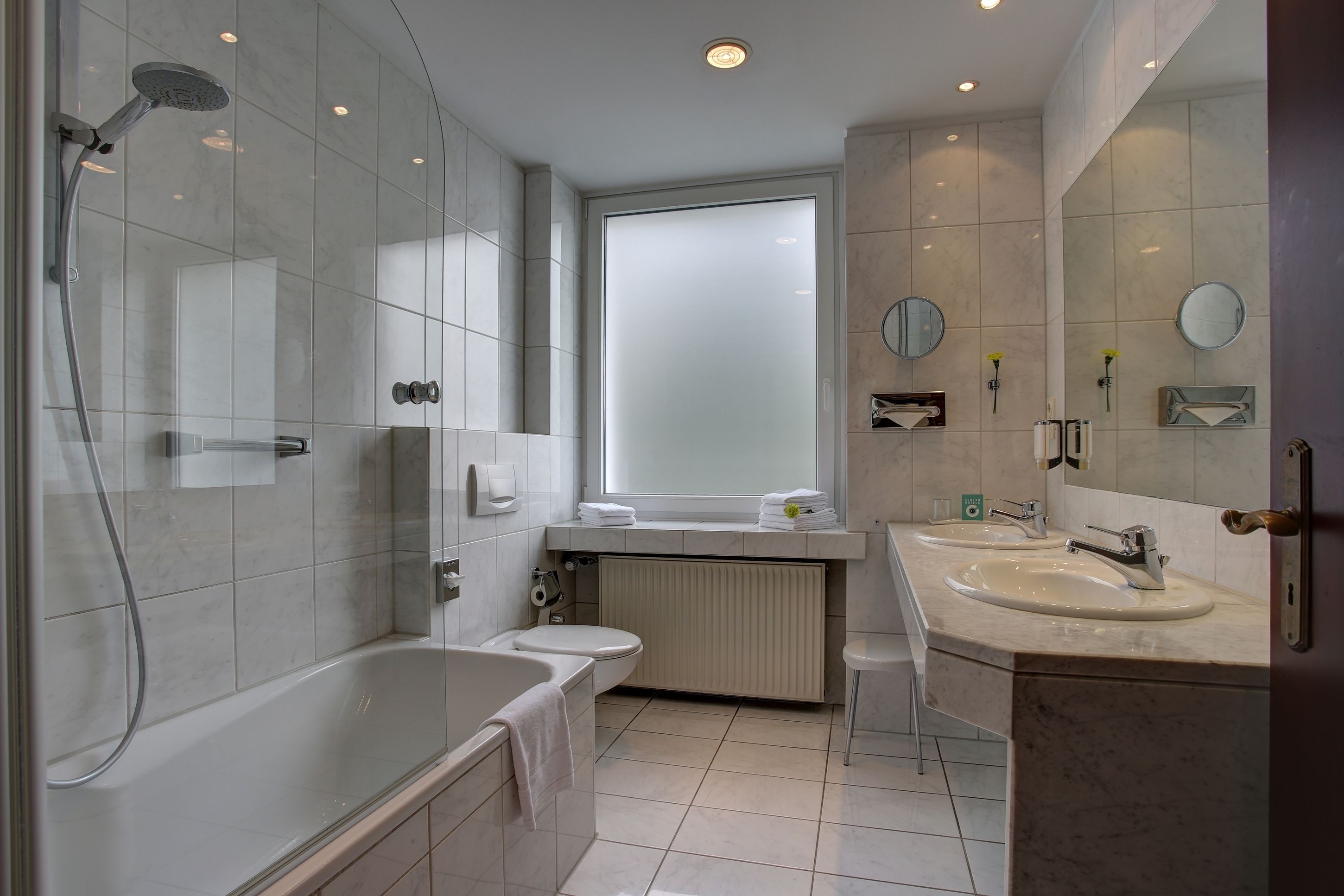 A modern bathroom with a bathtub, toilet, and two sinks.