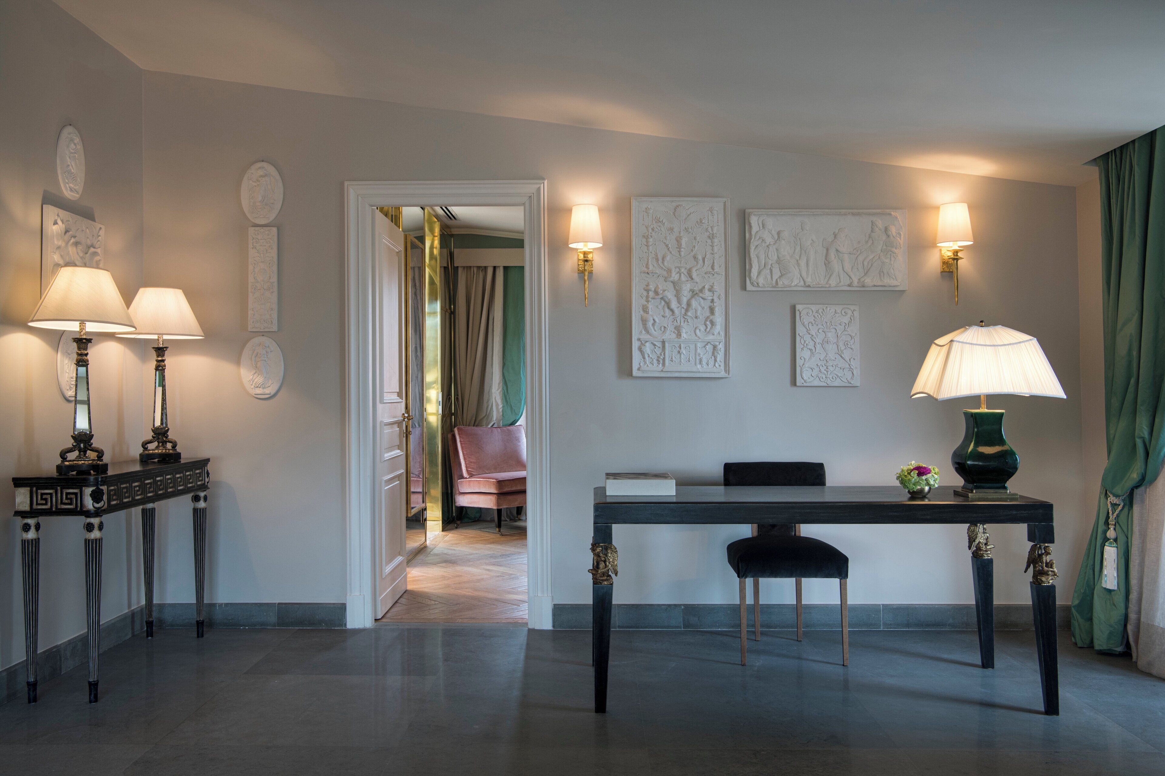 Un lobby moderno de hotel con zona de comedor, dos lámparas fijadas a la pared y una cortina verde.