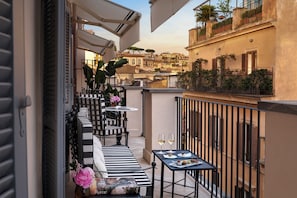 A balcony with outdoor furniture, a table with glasses, and a book.