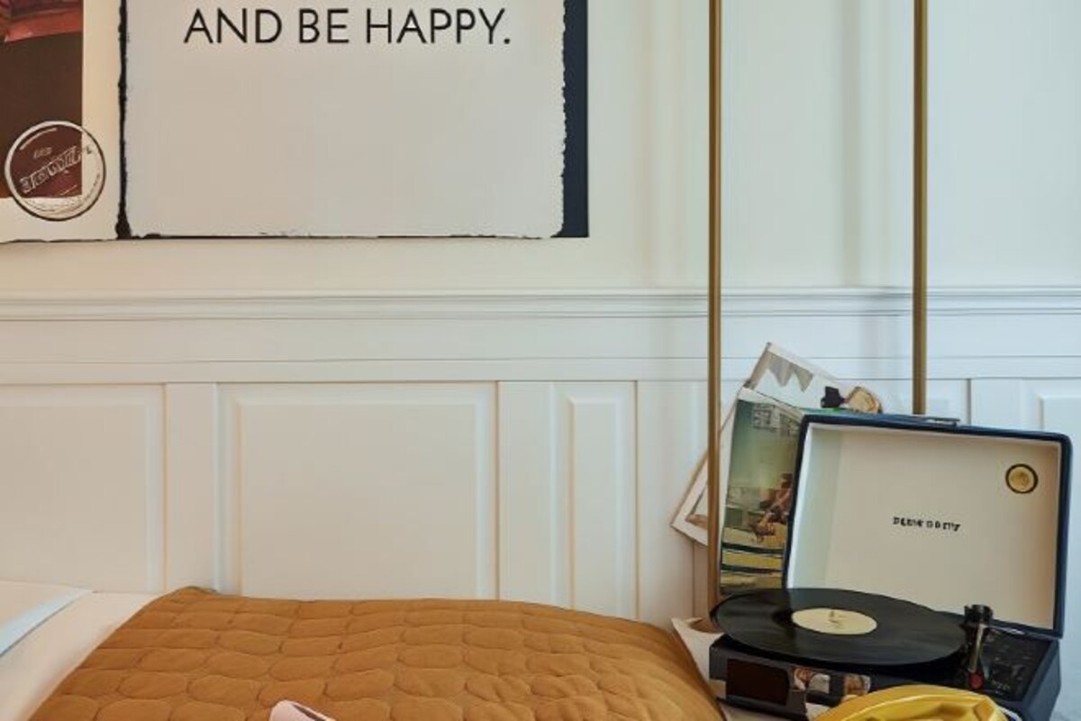A bedroom with a bed, a record player, and a poster on the wall.