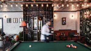 A billiards table in a room with a green felt surface, surrounded by wooden furniture and a patterned wall. - Max Brown Hotel Midtown, part of Sircle Collection (Düsseldorf)