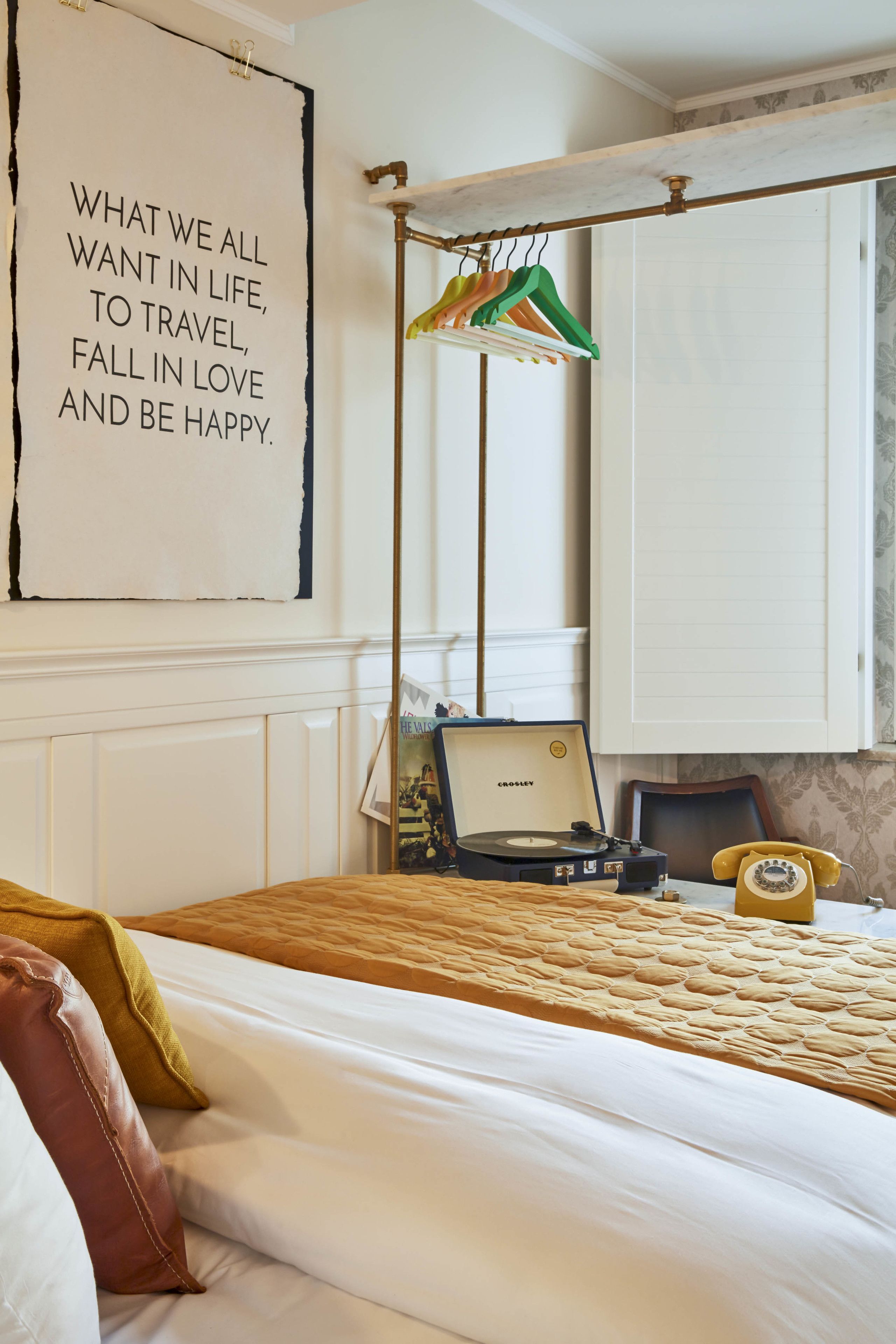 Un dormitorio con una cama, un teléfono antiguo, un tocadiscos y una pared con una cita inspiradora.