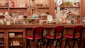 A bar area with wooden shelves, red bar stools, and a patterned floor. - Max Brown Hotel Midtown, part of Sircle Collection (Düsseldorf)