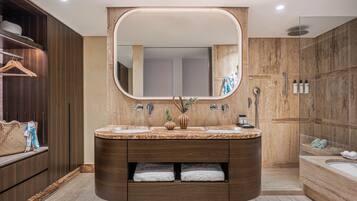 A modern bathroom with a large mirror, dual sinks, and a walk-in shower.