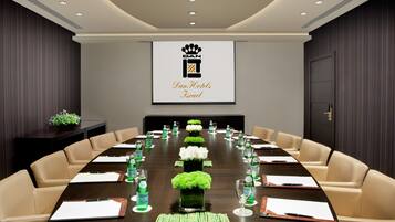 A conference room with a long table, beige chairs, and a logo on the wall.