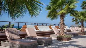 A sun deck with lounge chairs and a wooden deck, overlooking the sea. - Dan Accadia Hotel (Herzliya)