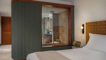 A hotel room with a large bed, a wooden headboard, a mirror, and a green accent wall.