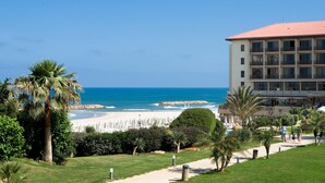 A beachfront hotel with a view of the ocean, a pool area, and a pathway leading to the beach. - Dan Accadia Hotel (Herzliya)