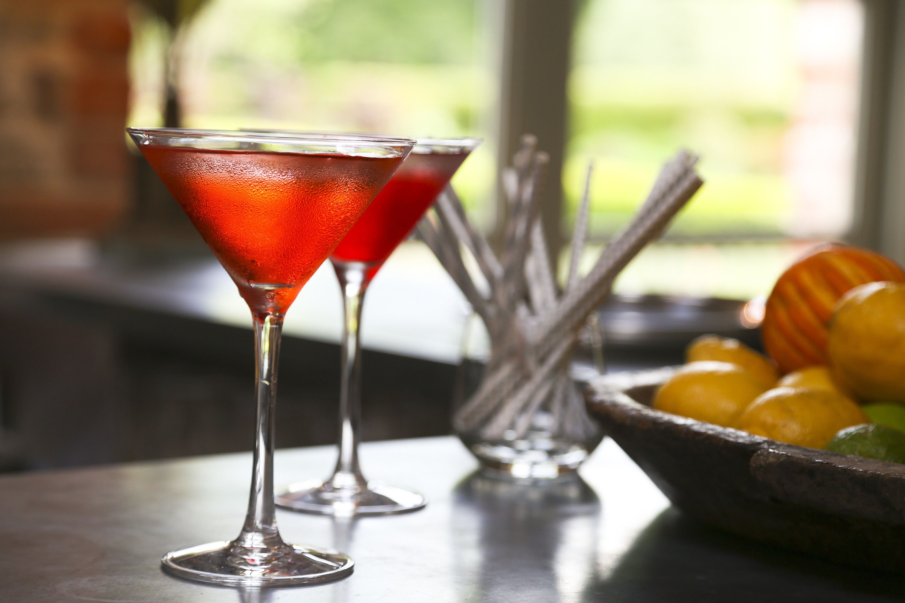 Two martini glasses with a red drink on a table.
