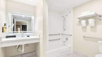 A modern bathroom with a white sink, mirror, shower, and toilet.