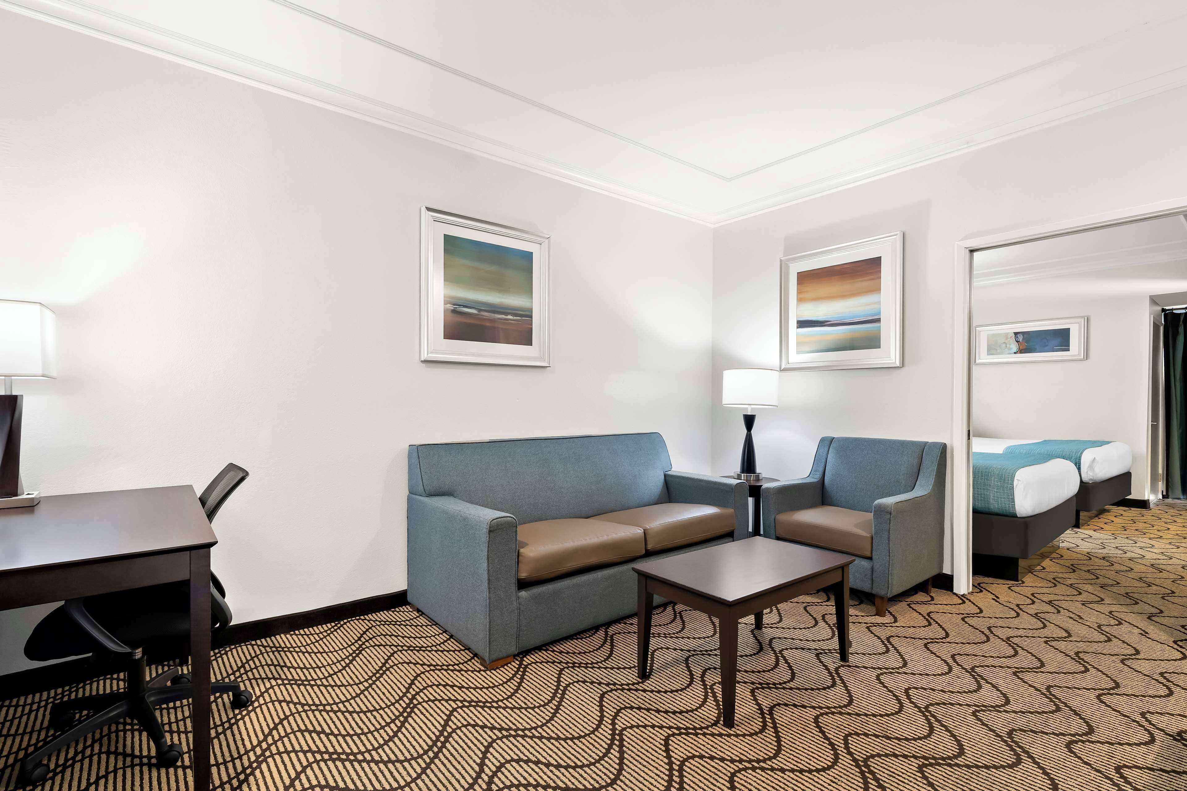 A hotel room with a sofa, a small table, a desk, and a bed.