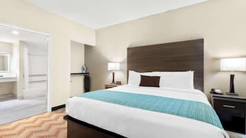 A hotel room with a large bed, two bedside tables, a nightstand, a mirror, and a door leading to a bathroom.