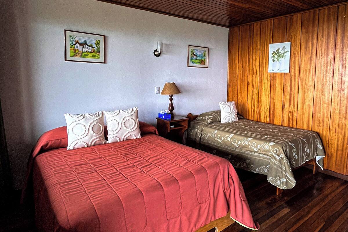 Una habitación con dos camas, suelo de madera y paneles de madera.