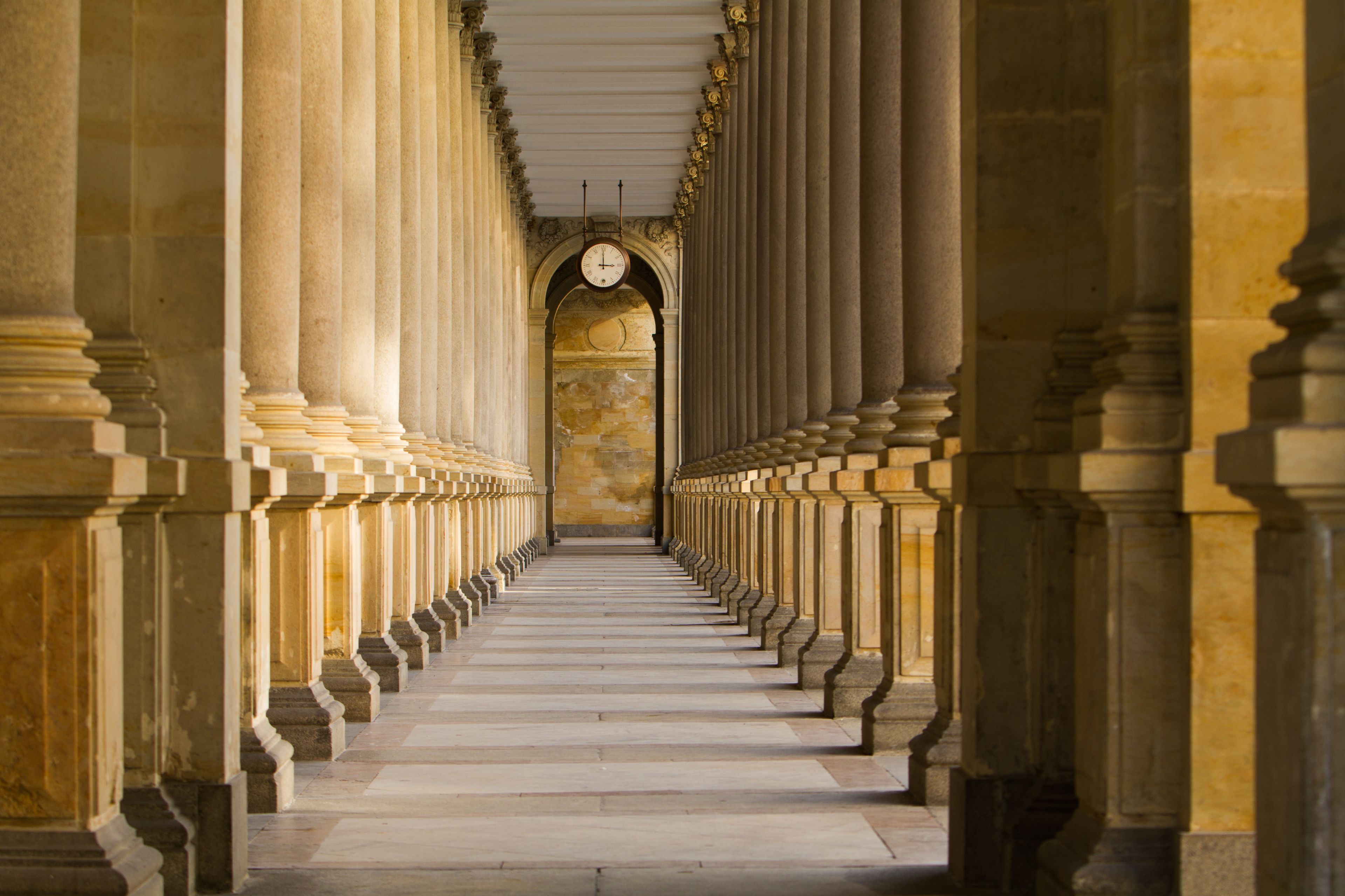 A corridor with evenly spaced columns and a central archway.