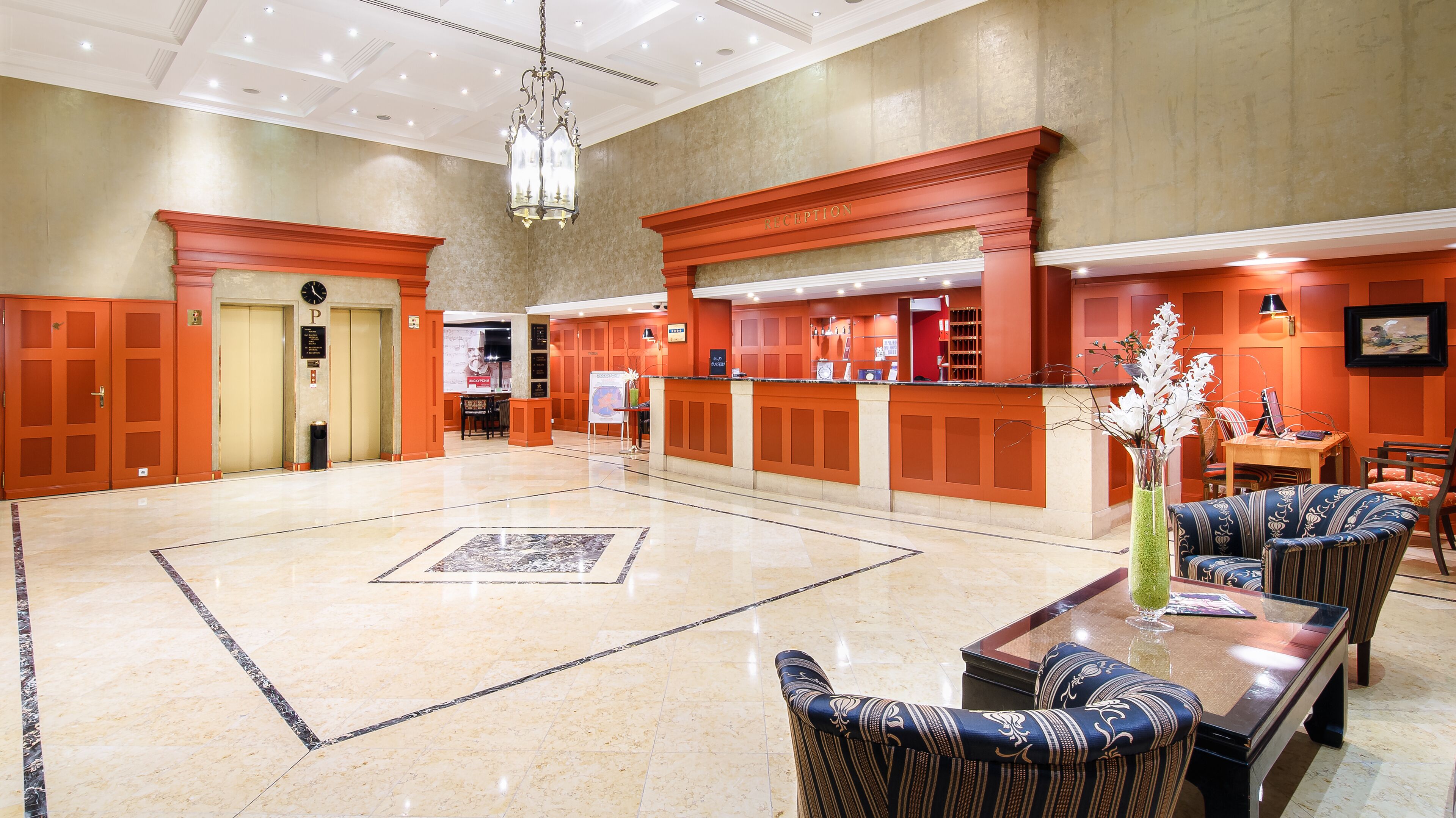 A spacious lobby with a reception desk, seating area, and a large marble floor.