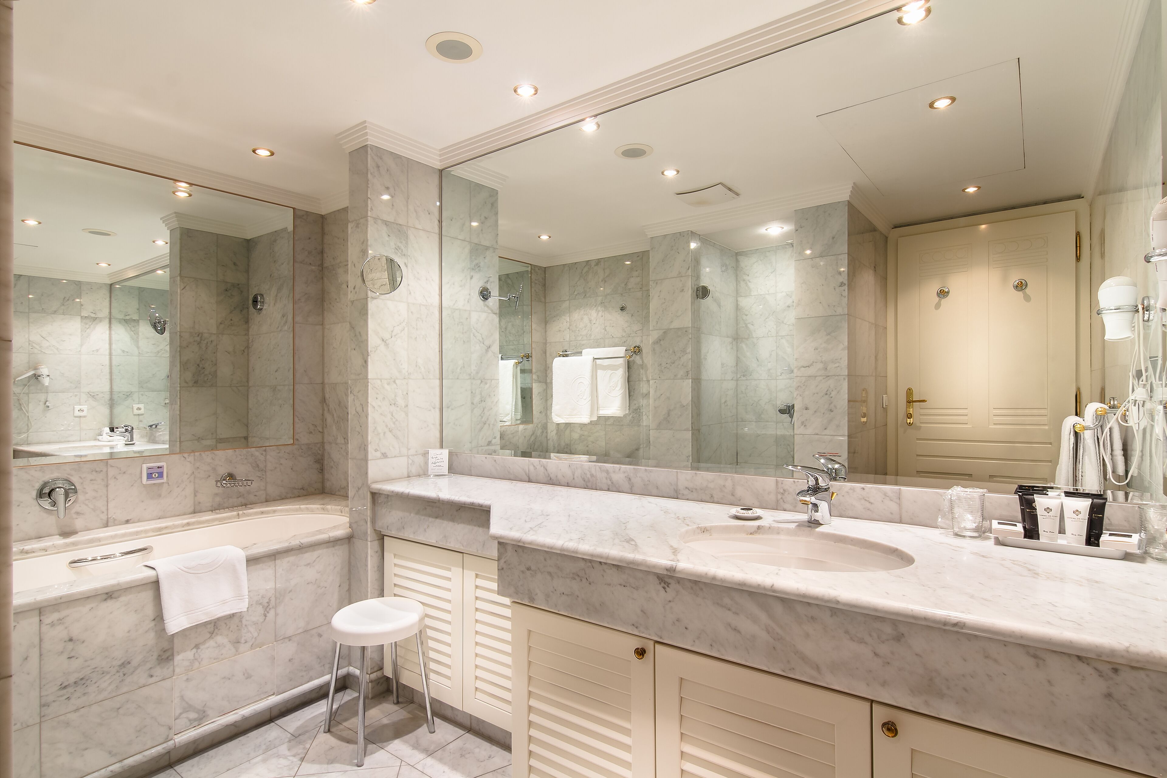 Une salle de bain moderne avec un grand miroir, une baignoire, un lavabo et des toilettes.