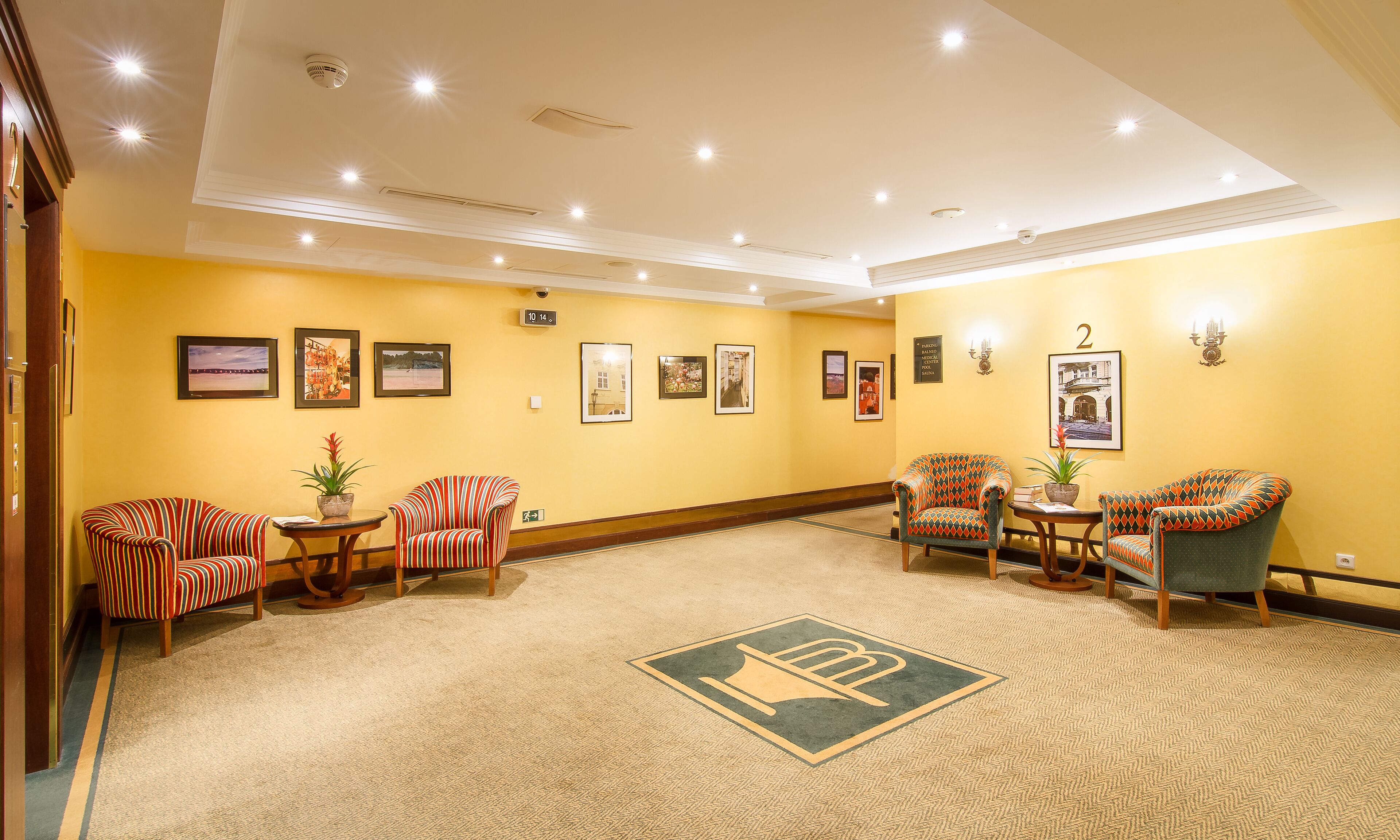 A lobby with striped armchairs, a reception desk, and framed pictures on the walls.