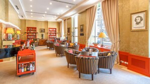 A hotel lobby with striped armchairs, a red cart with bottles, and bookshelves. - Dvorak Spa & Wellness (Karlovy Vary)