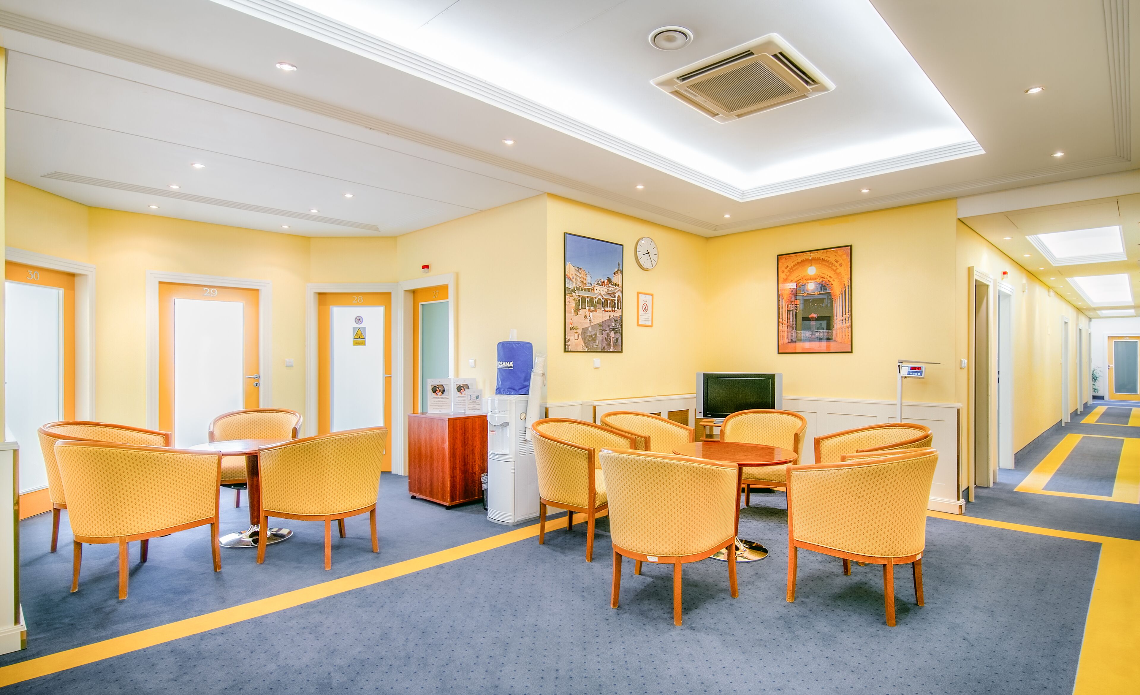 A hotel lobby with a reception desk, seating area, and a clock on the wall.