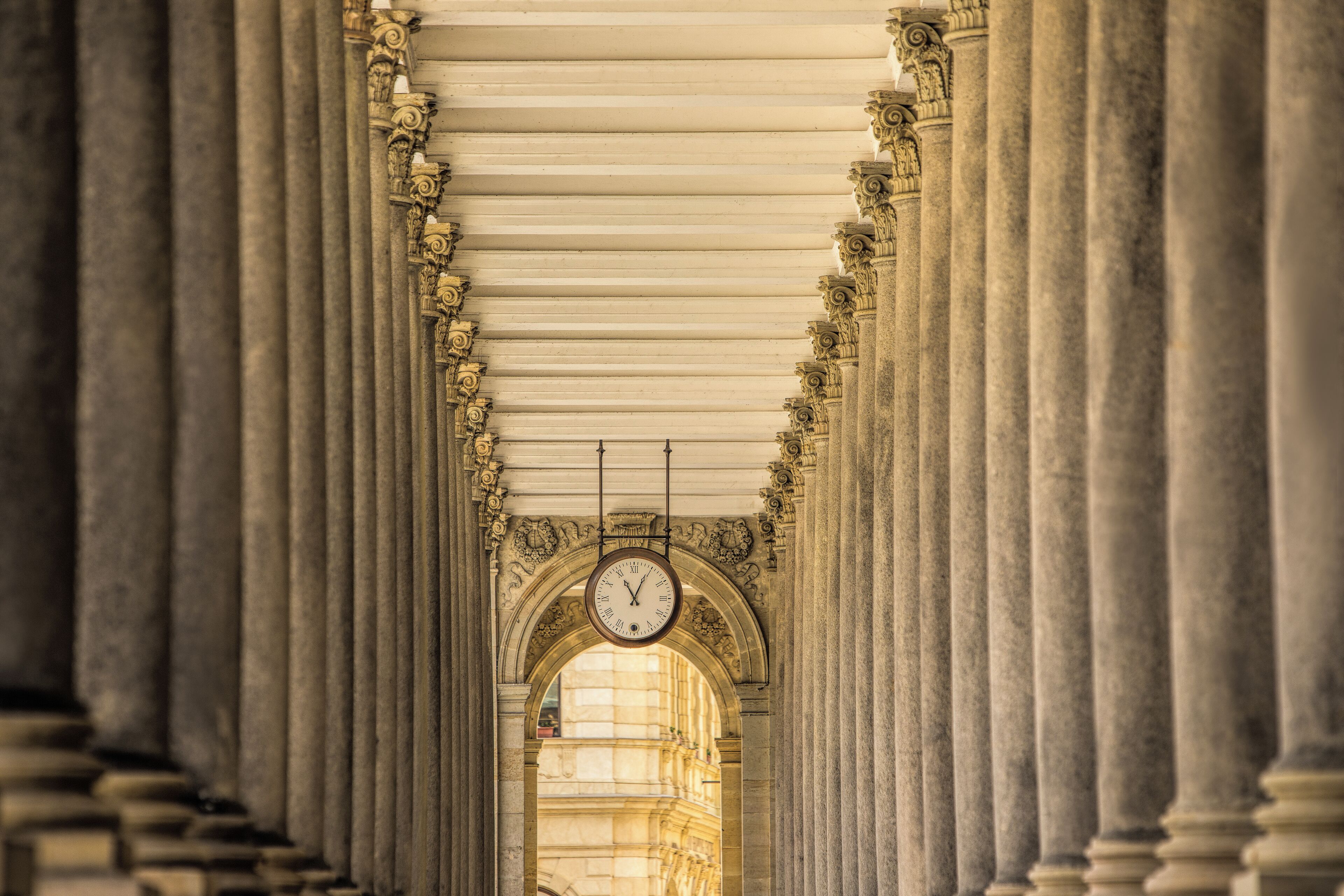 A corridor with classical architecture, featuring columns and an arched ceiling.