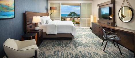 A hotel room with a bed, a desk, a chair, a TV, and a view of the outdoors.