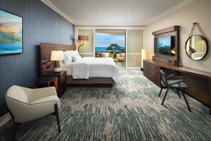 A hotel room with a bed, a desk, a chair, a TV, and a view of the outdoors.