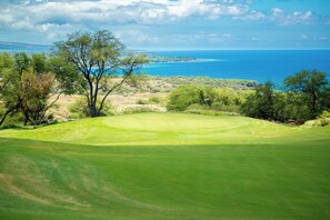 A golf course with a view of the ocean and distant land.