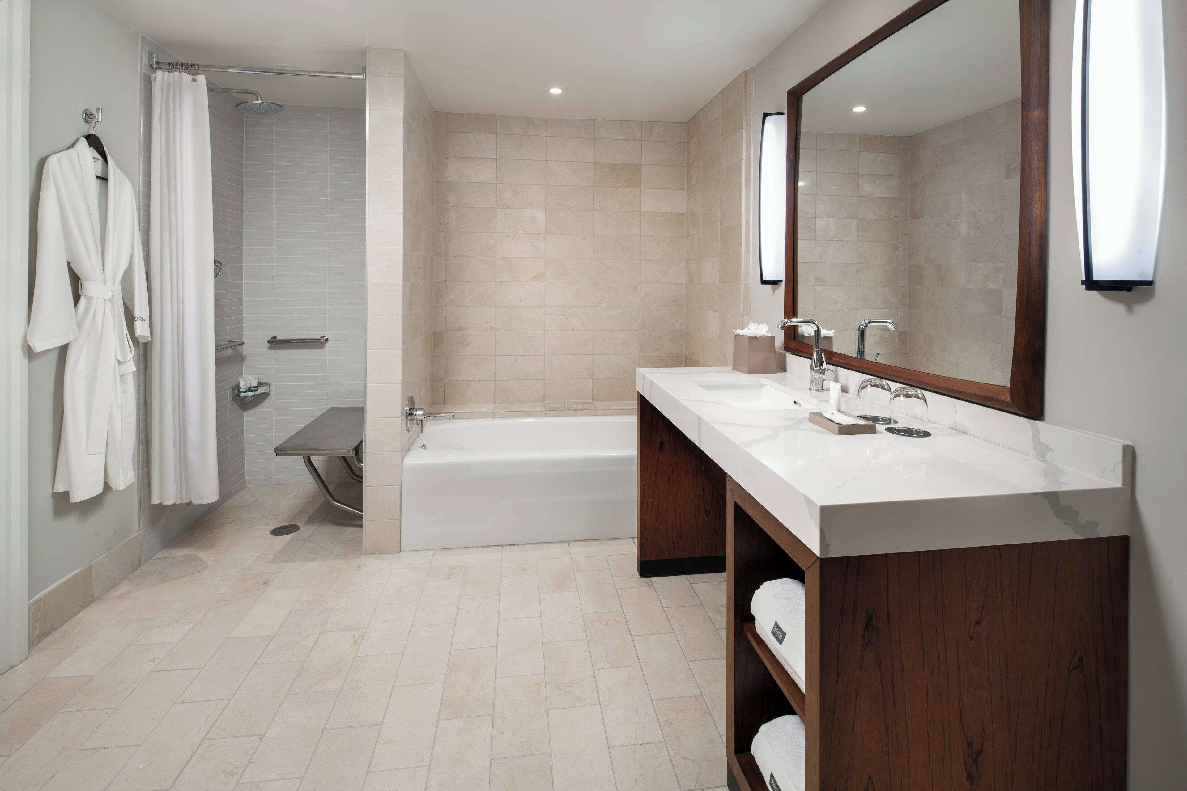 Un baño moderno con bañera, un espejo grande y tocador con lavamanos.