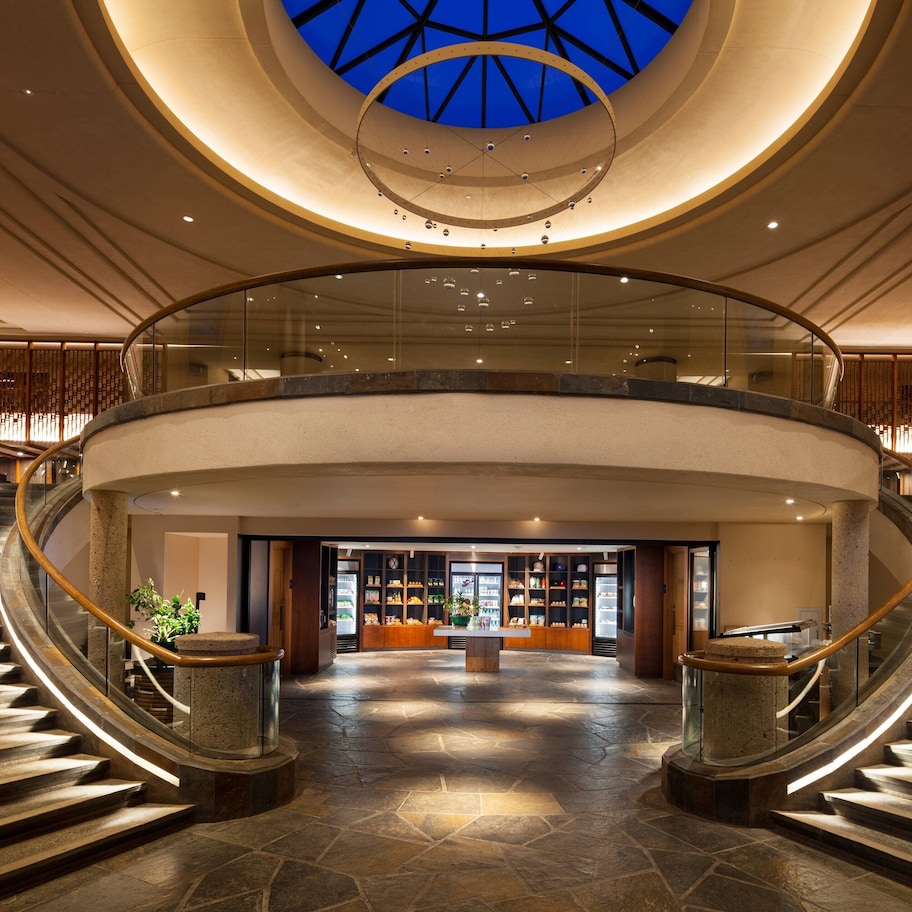 A spacious lobby with a central staircase, a glass railing, and a skylight.
