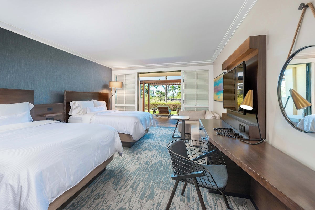 Une chambre d’hôtel avec deux lits, un bureau avec une chaise, une petite table, une lampe et un grand miroir.