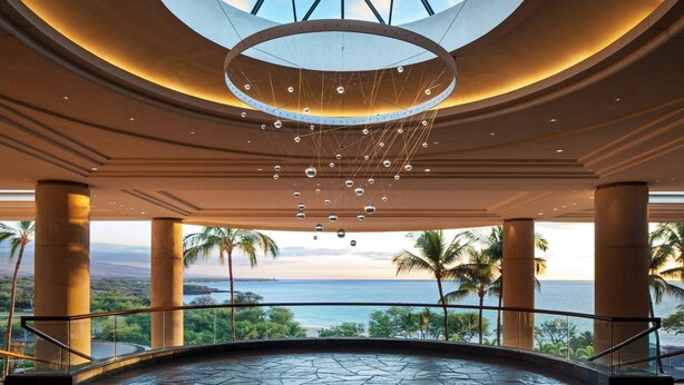 Un vaste atrium doté d’une grande verrière circulaire, d’un luminaire sphérique suspendu et offrant une vue sur l’océan.