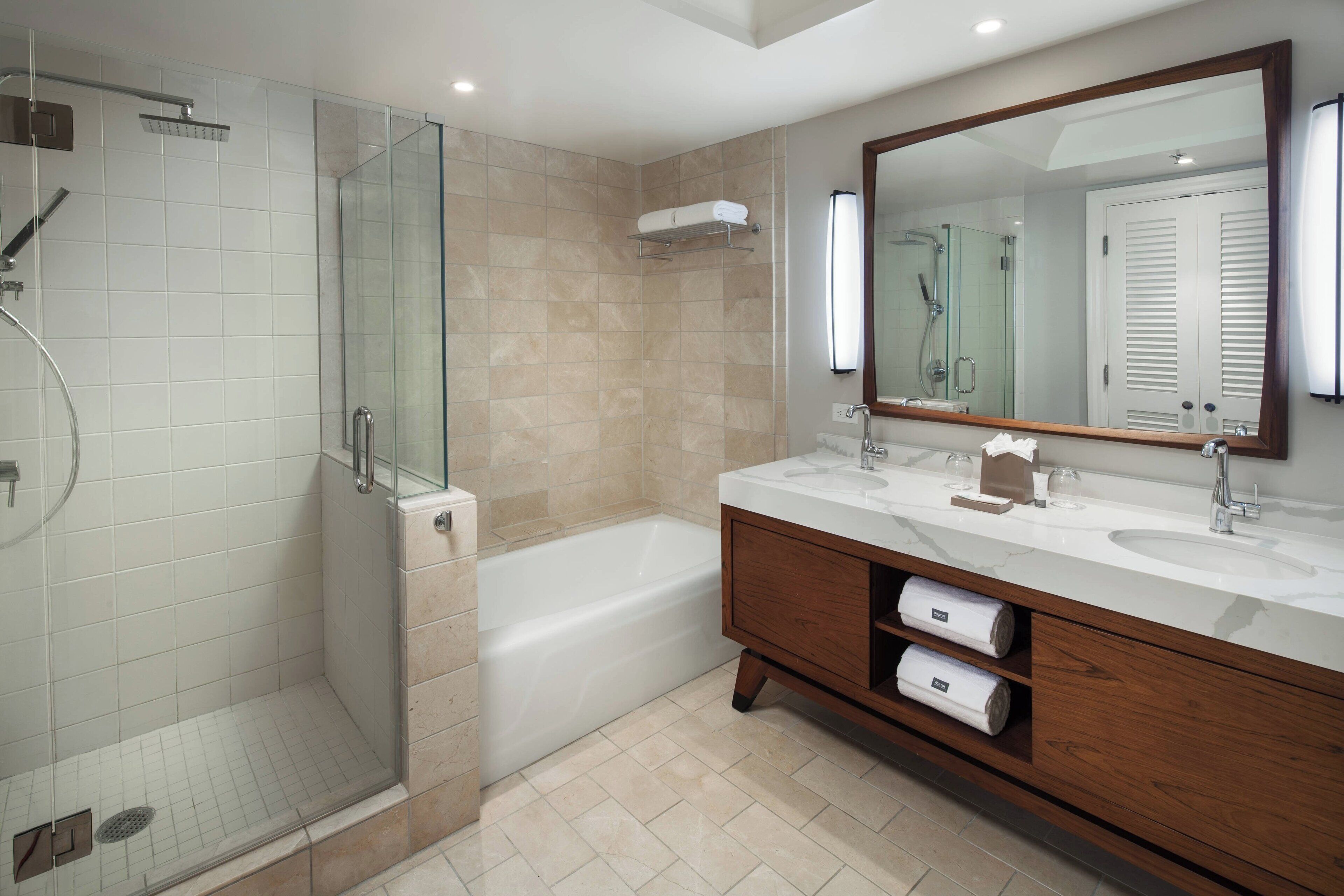 A modern bathroom with a glass-enclosed shower, a standalone bathtub, and a vanity with two sinks.