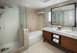 A modern bathroom with a glass-enclosed shower, a standalone bathtub, and a vanity with two sinks.
