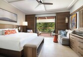 A modern hotel room with a large bed, a sofa, a dining table, and a balcony with a view.