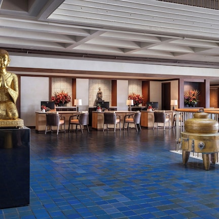 A lobby with a large golden Buddha statue, reception desks, and a traditional fish-shaped water heater.