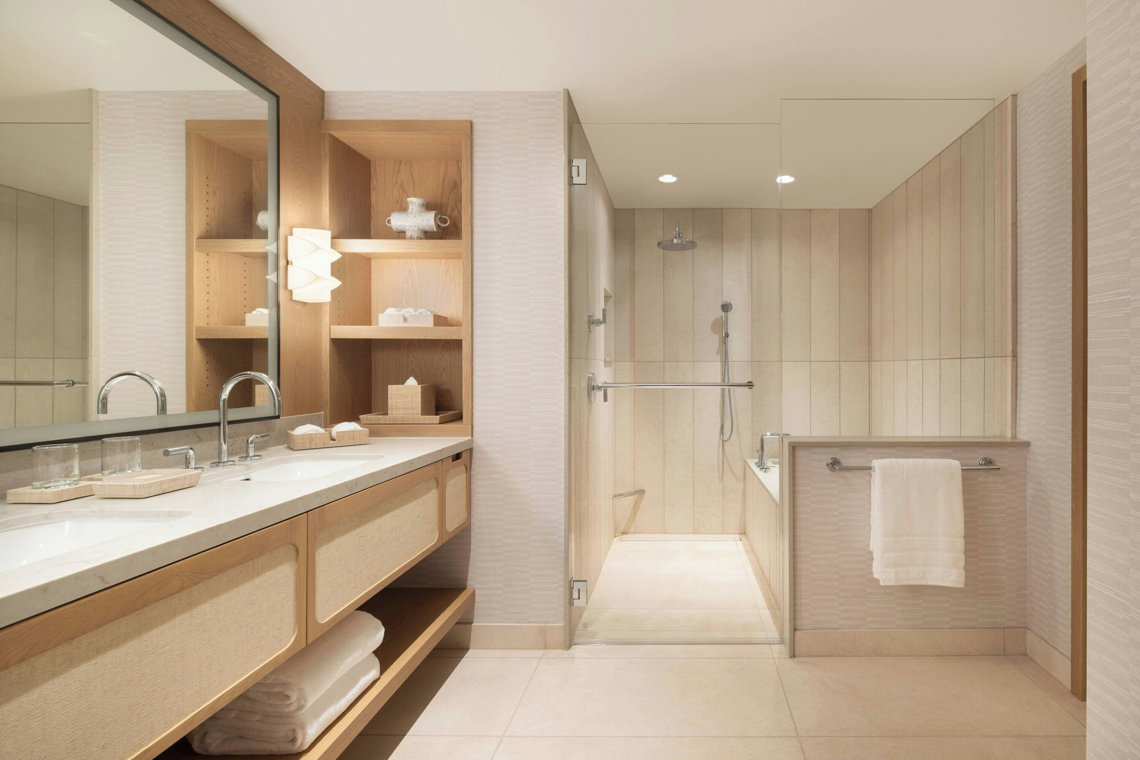 A modern bathroom with a wooden vanity, a large mirror, a shower area, and a towel rack.